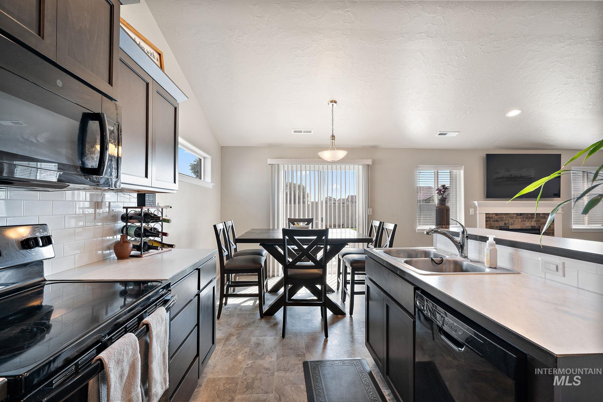 Kitchen featuring black appliances, decorative backsplash, plenty of natural light, decorative light fixtures, and a textured ceiling