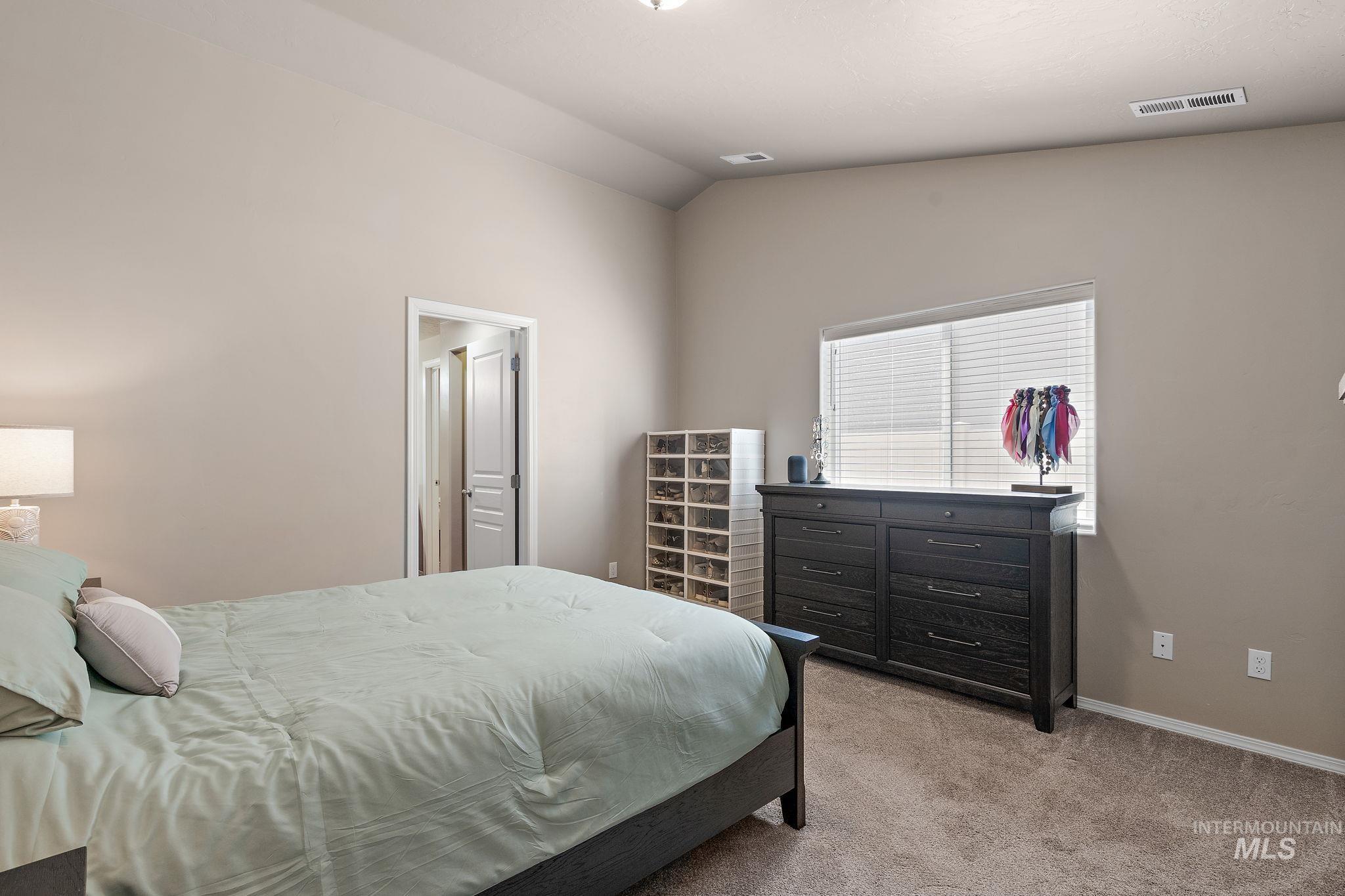 Bedroom with light carpet and vaulted ceiling