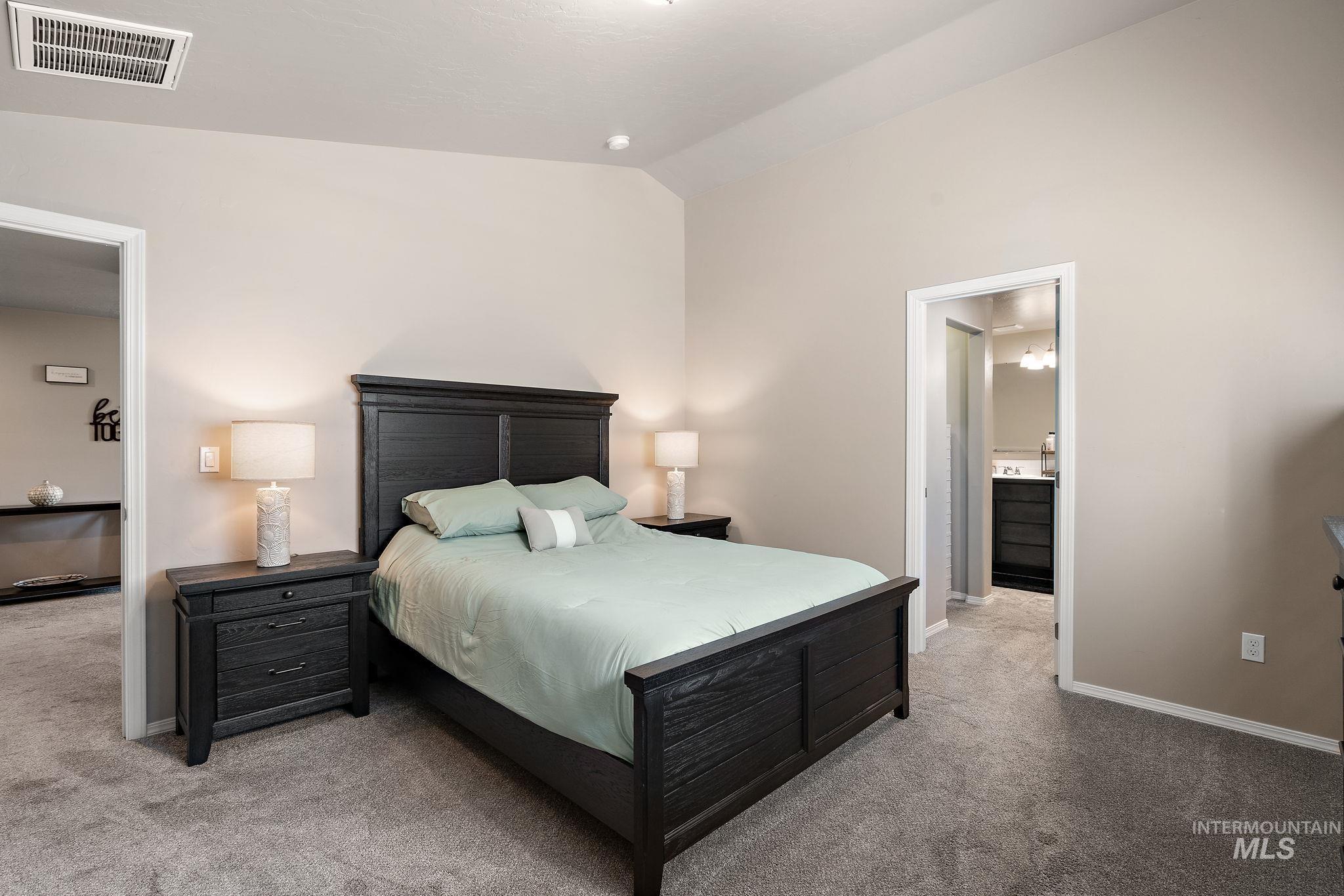 Bedroom featuring light carpet and vaulted ceiling