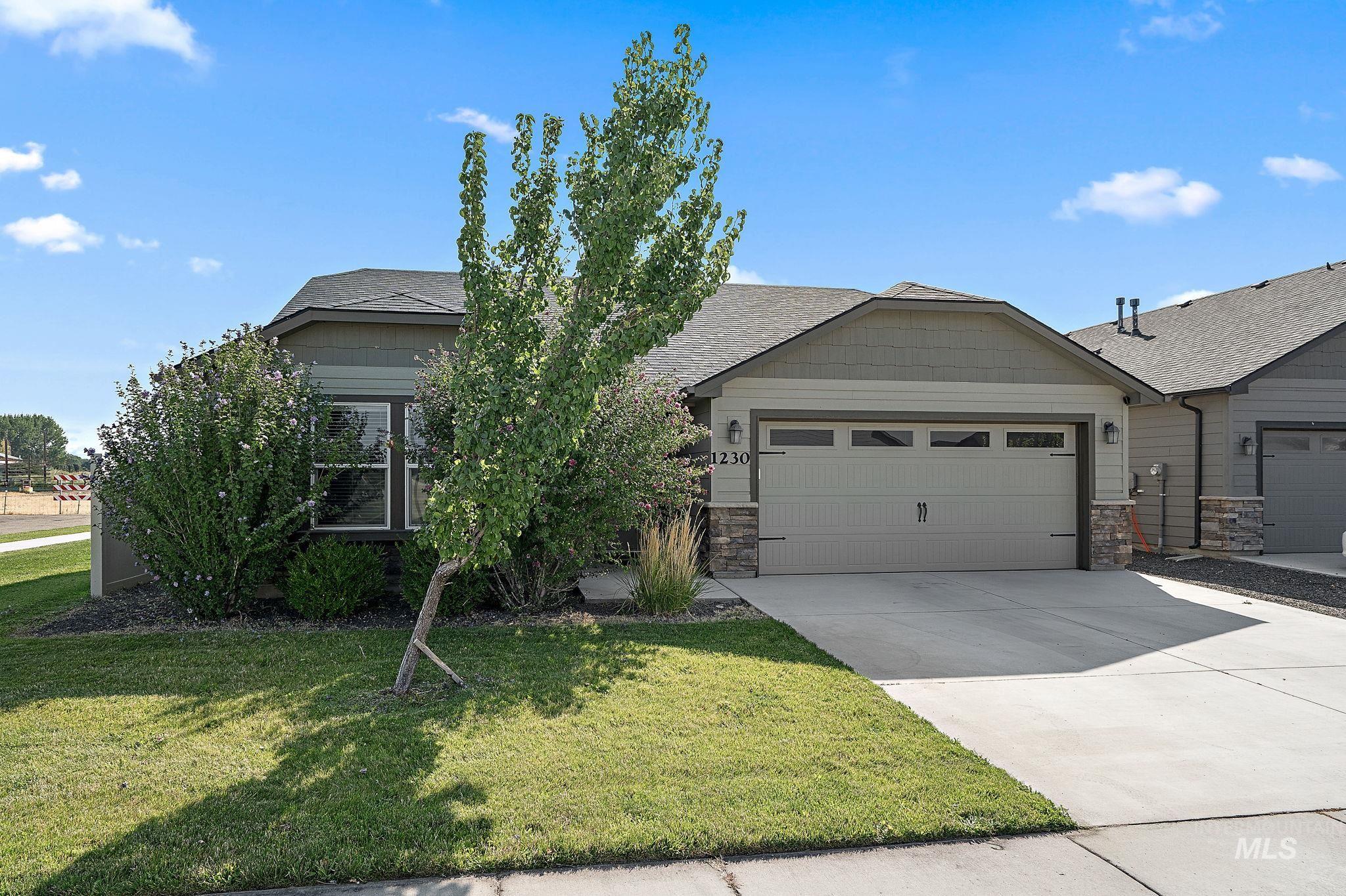View of front of property with driveway, an attached garage, stone siding, and a front lawn