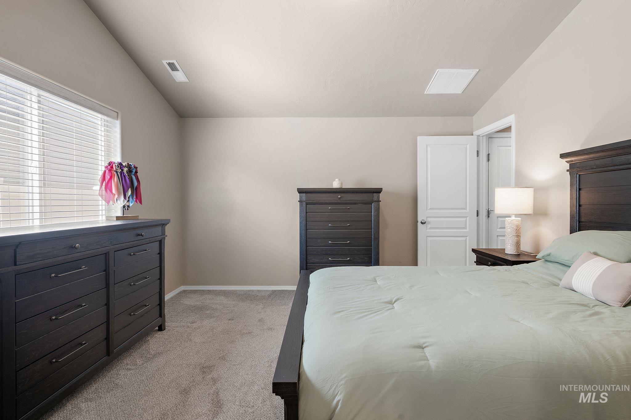 Bedroom featuring light carpet and lofted ceiling