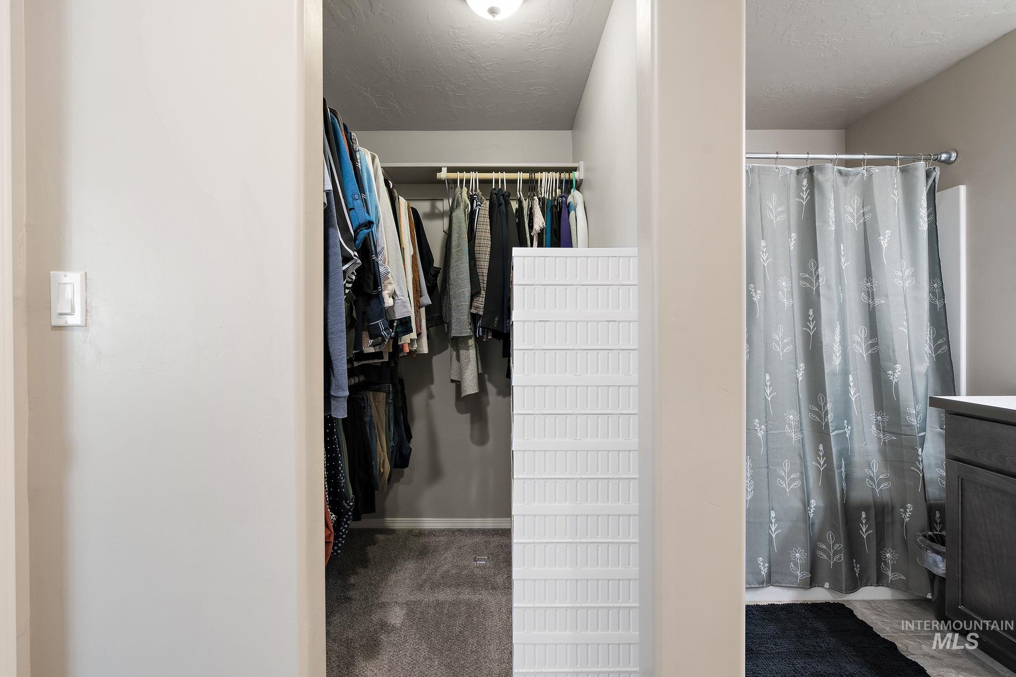 Bathroom with a spacious closet, vanity, a textured ceiling, and a shower with curtain