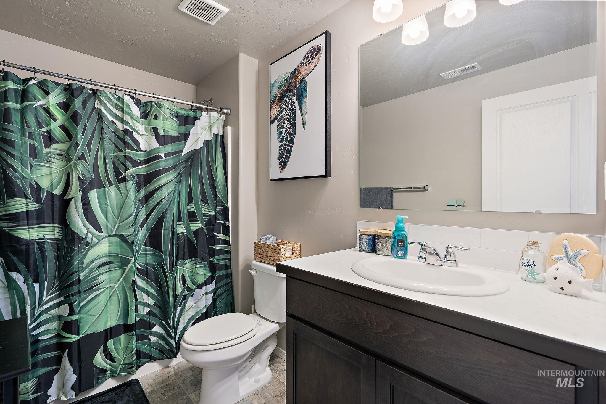 Full bathroom with vanity, a textured ceiling, and a shower with curtain