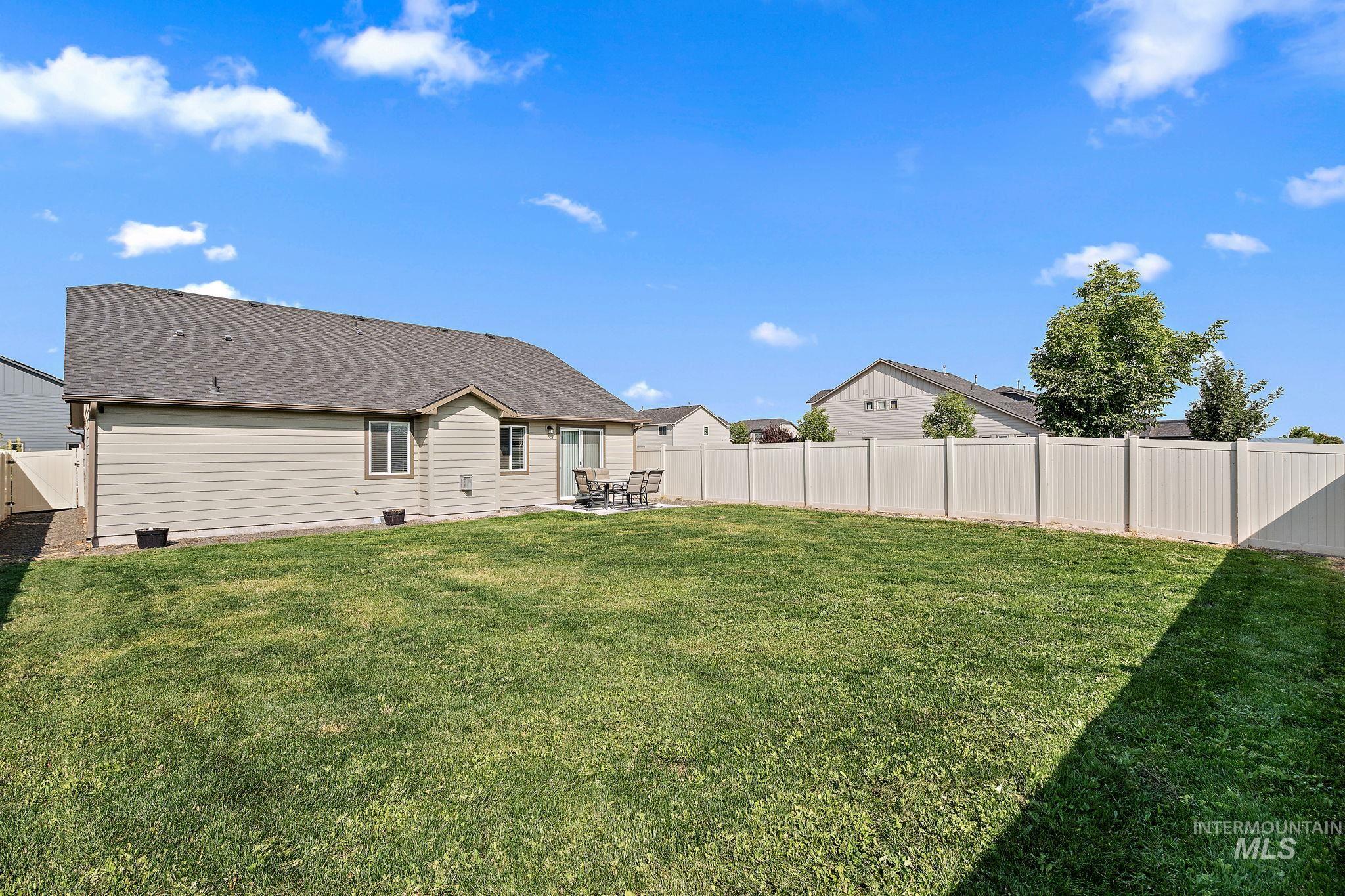 Rear view of house with a patio area, a fenced backyard, and roof with shingles