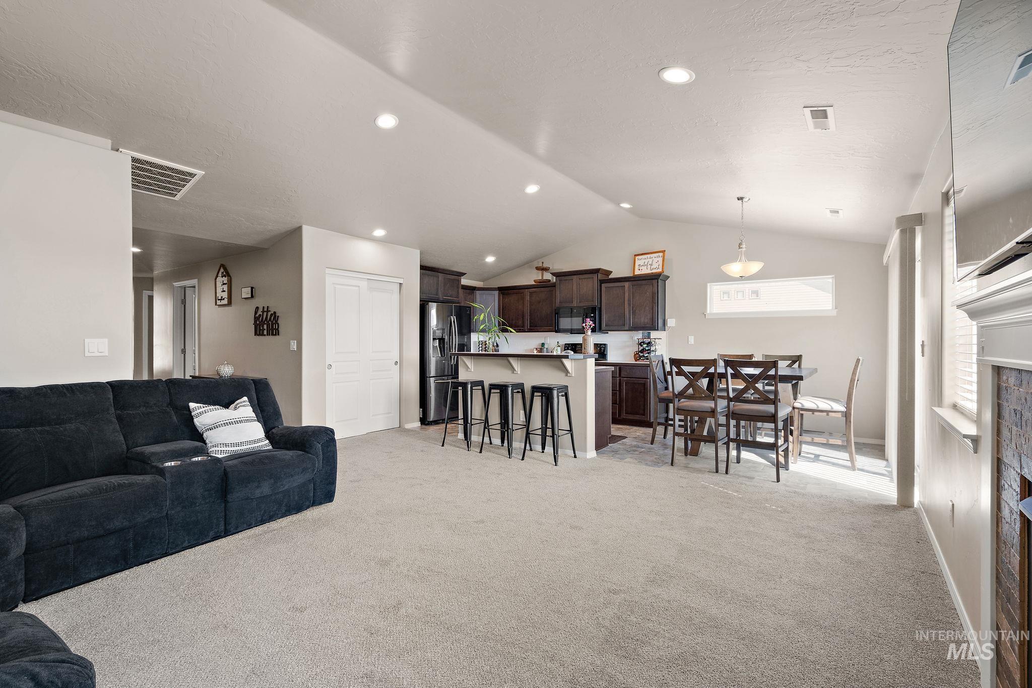 Living room with light colored carpet, vaulted ceiling, recessed lighting, and a textured ceiling