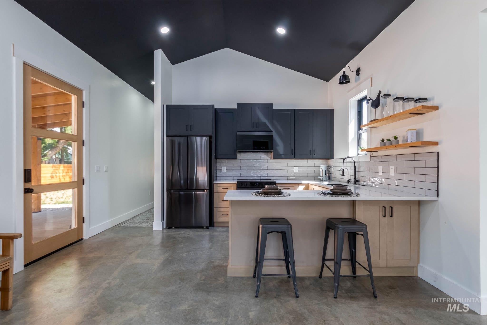 Kitchen with black appliances, tasteful backsplash, a breakfast bar area, a peninsula, and open shelves
