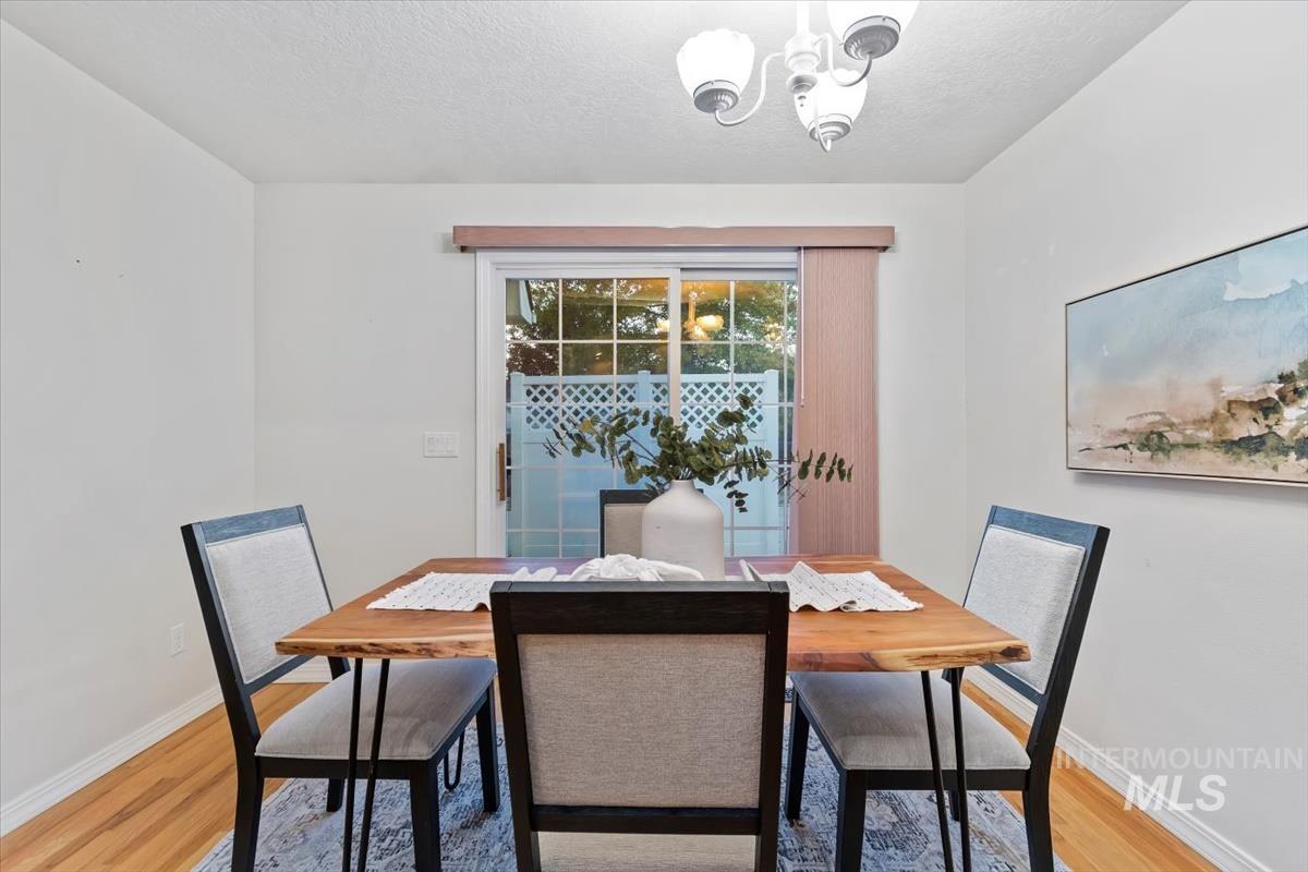 Dining space with a chandelier, light wood-style floors, and a textured ceiling