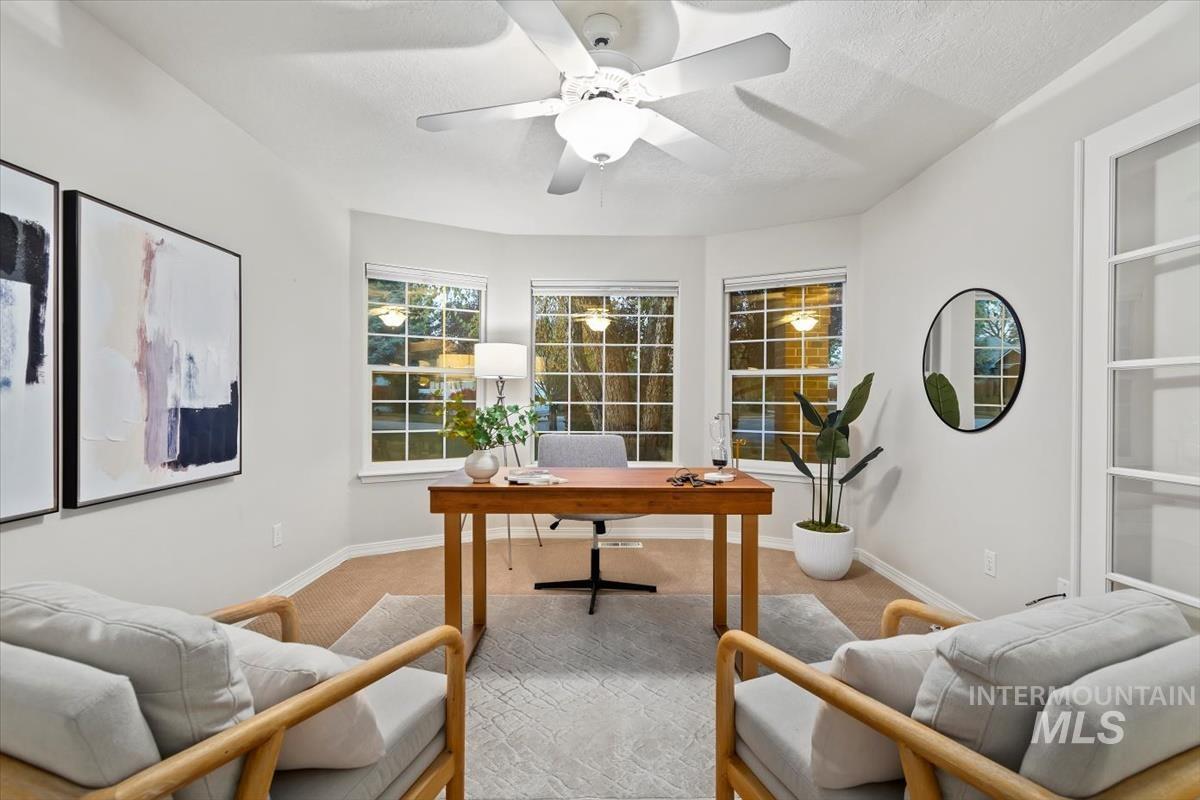 Carpeted office with baseboards and a ceiling fan