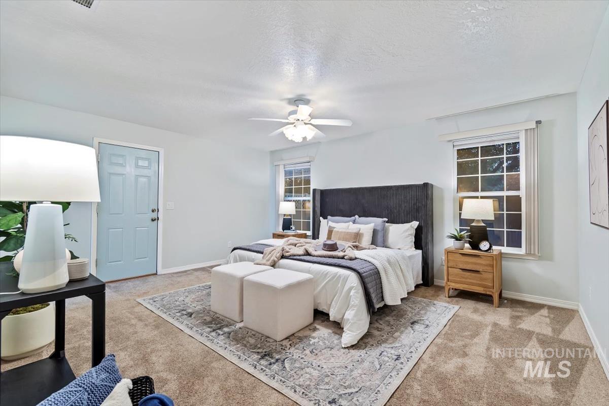 Bedroom with a ceiling fan, light carpet, and a textured ceiling