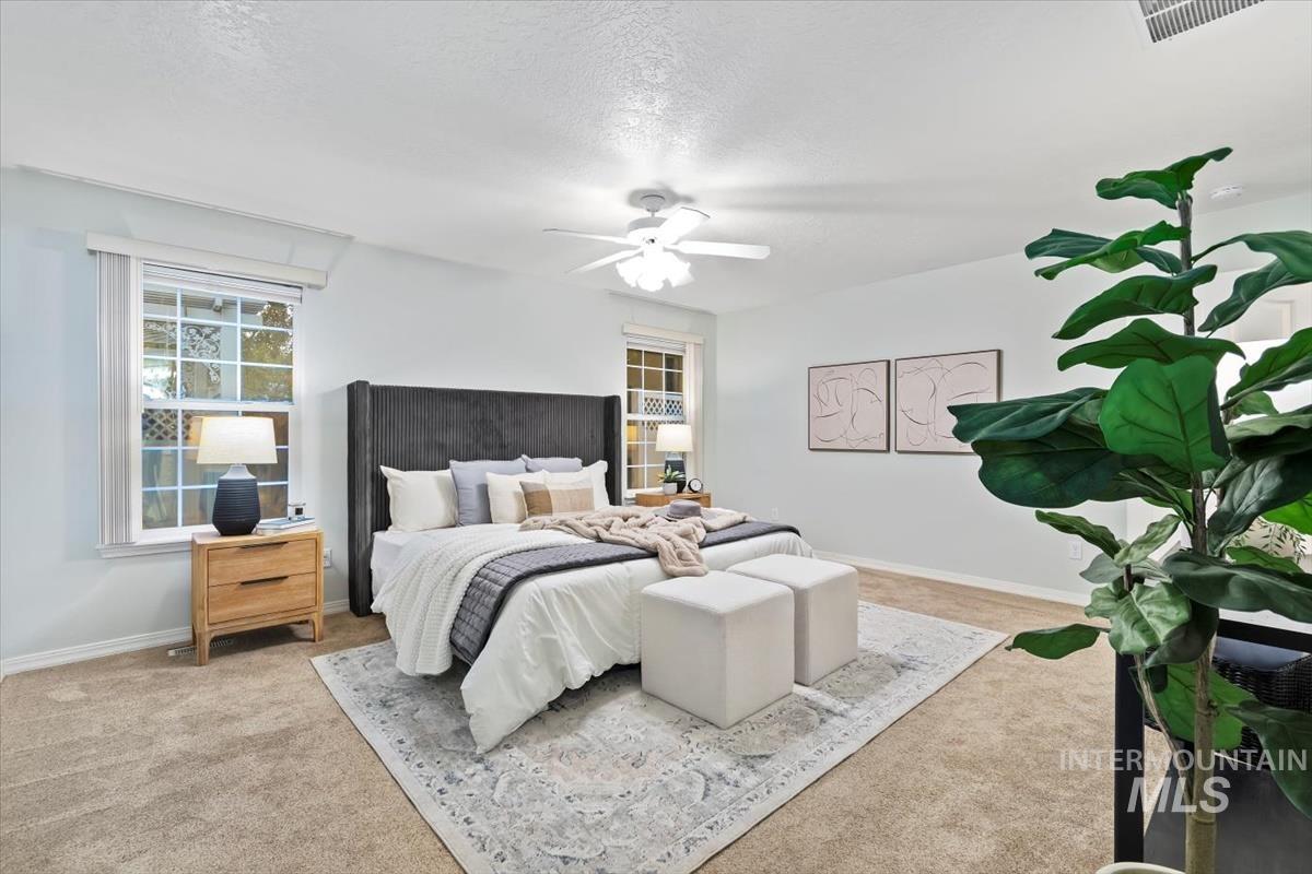 Bedroom with a textured ceiling, carpet flooring, and a ceiling fan