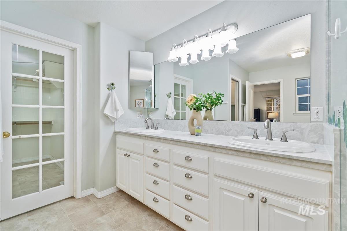 Bathroom featuring double vanity, light tile patterned flooring, and a spacious closet