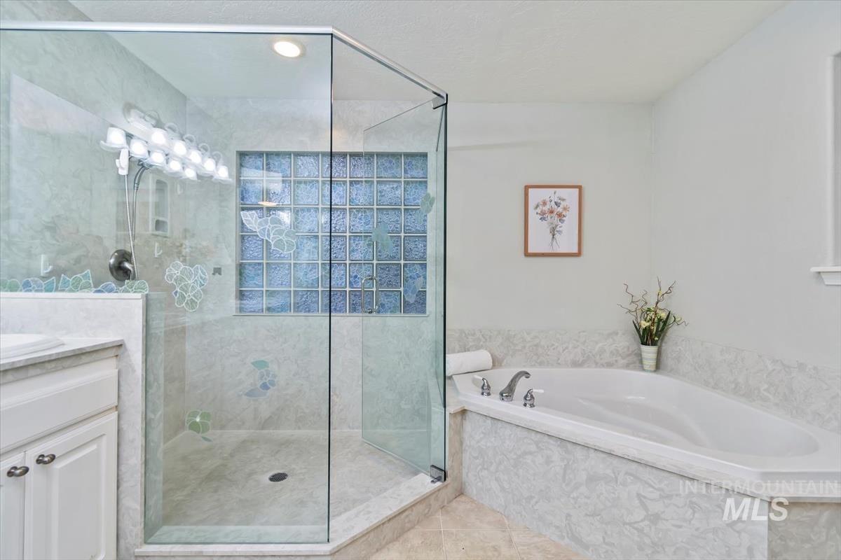 Bathroom with a stall shower, a garden tub, vanity, and tile patterned floors