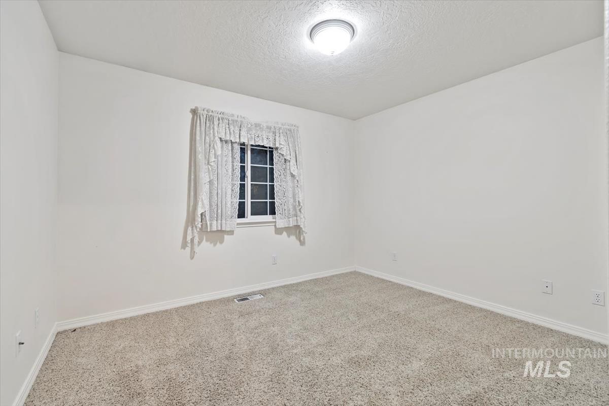 Empty room with carpet and a textured ceiling