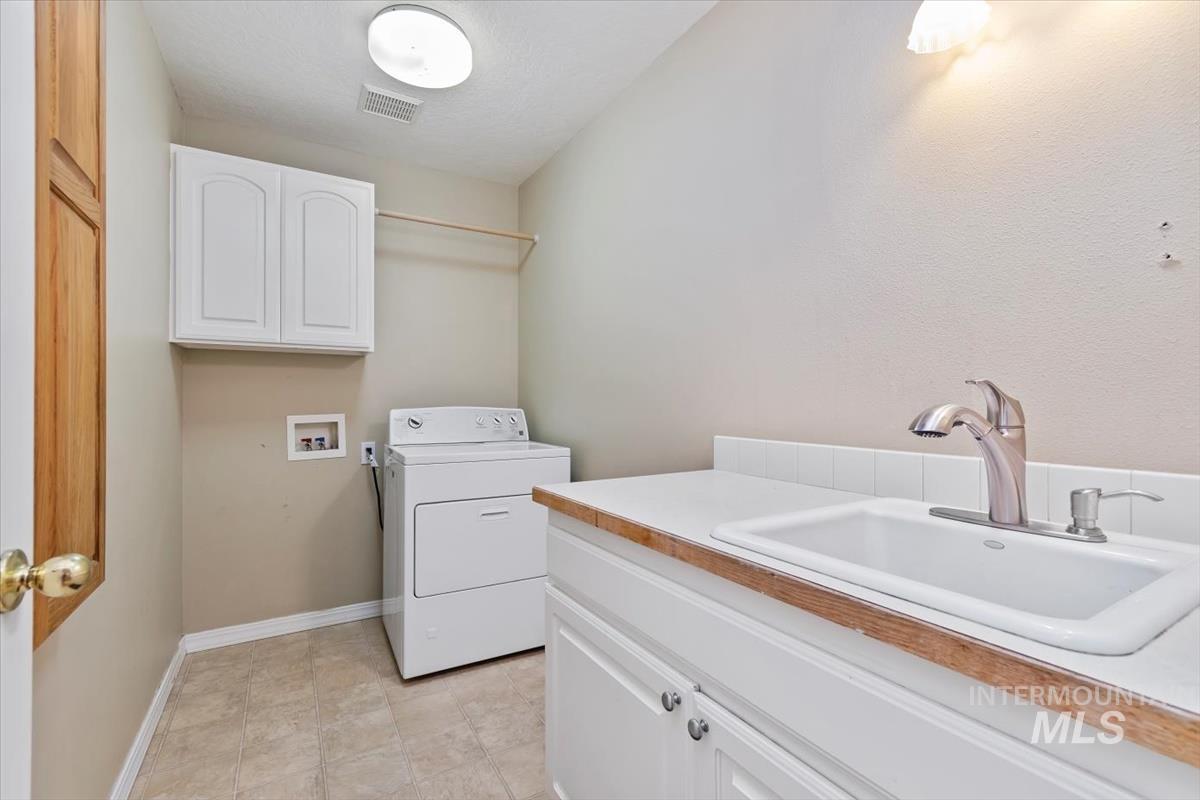 Laundry room featuring washer / dryer, cabinet space, and light tile patterned floors