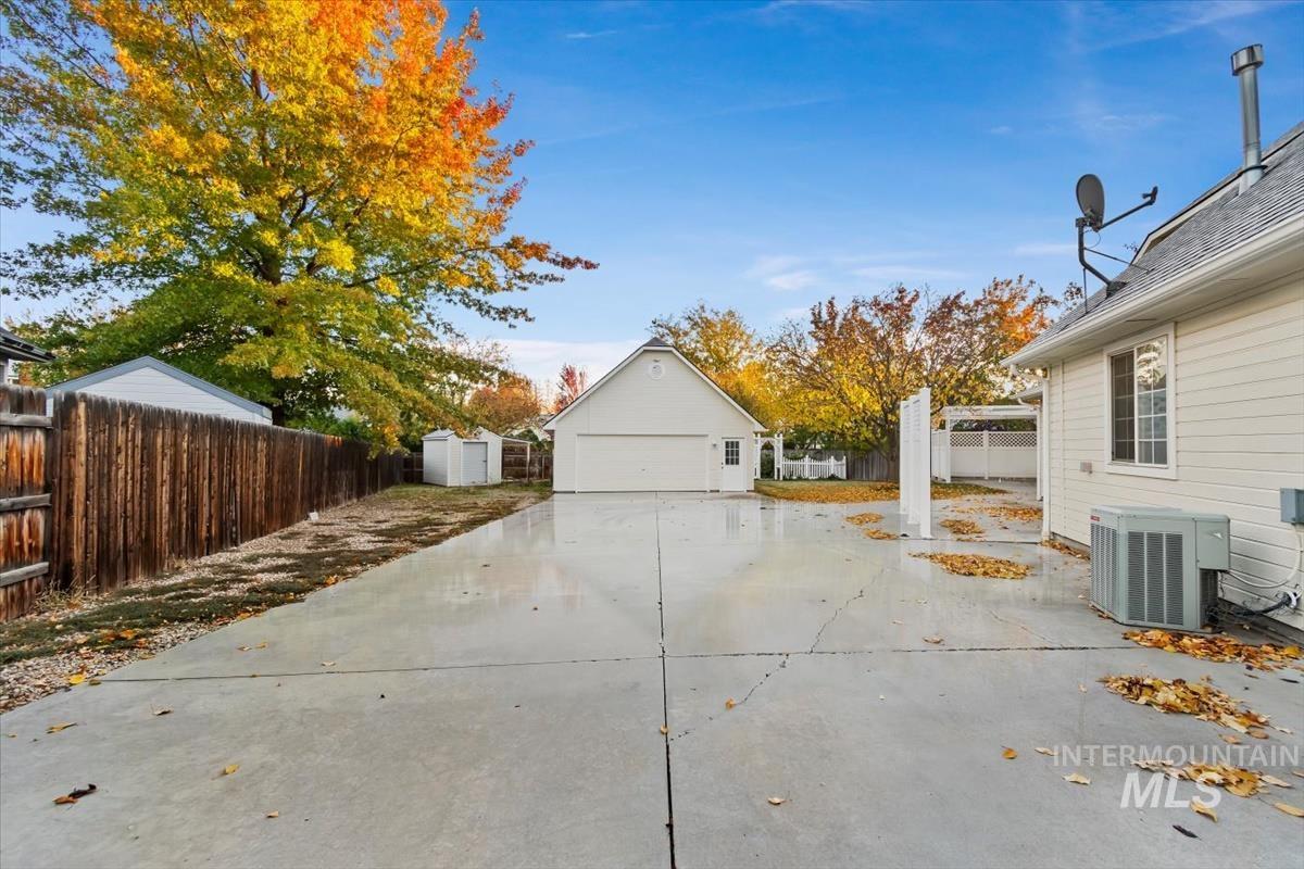 View of property exterior with a fenced backyard, a patio, a shed, and a detached garage