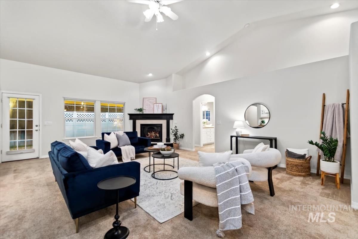 Living area featuring light colored carpet, a glass covered fireplace, recessed lighting, arched walkways, and high vaulted ceiling