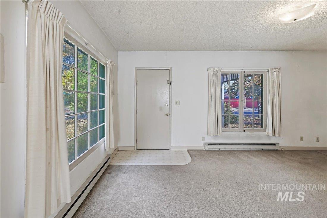 Carpeted foyer entrance featuring a baseboard radiator, a textured ceiling, healthy amount of natural light, and baseboard heating