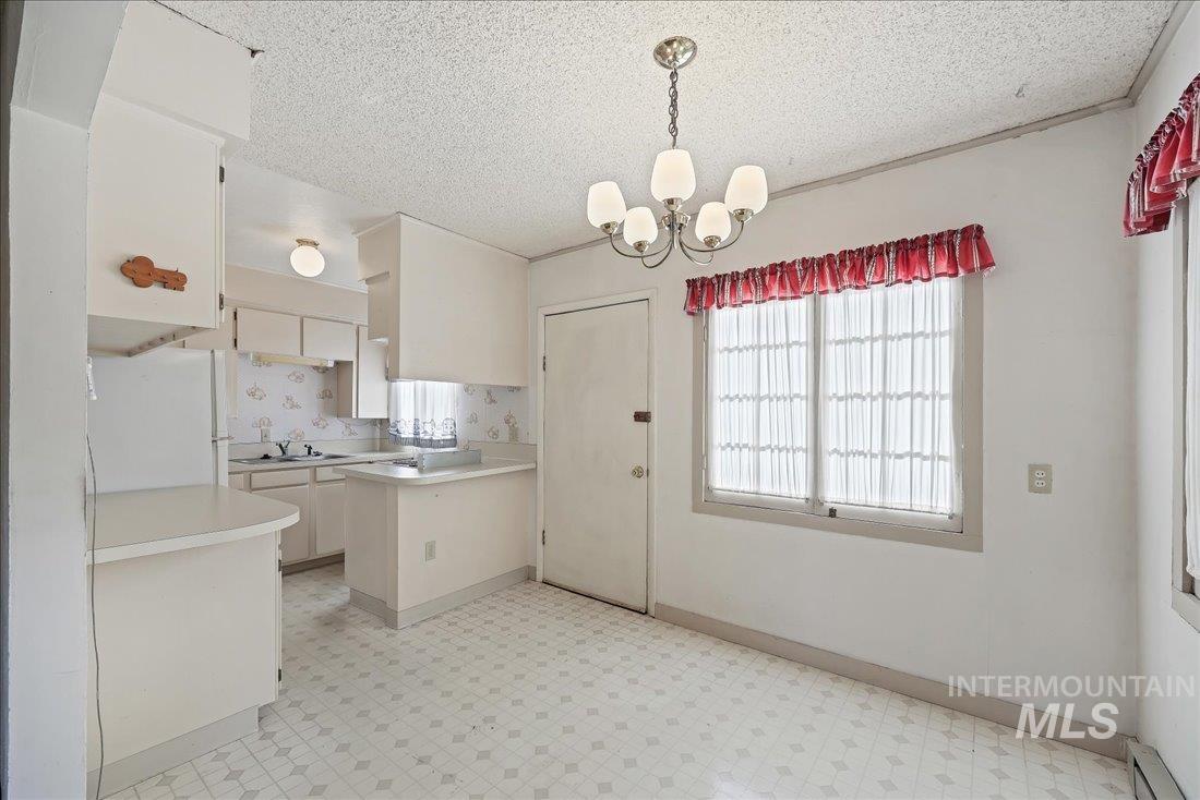 Kitchen featuring light floors, light countertops, freestanding refrigerator, hanging light fixtures, and plenty of natural light