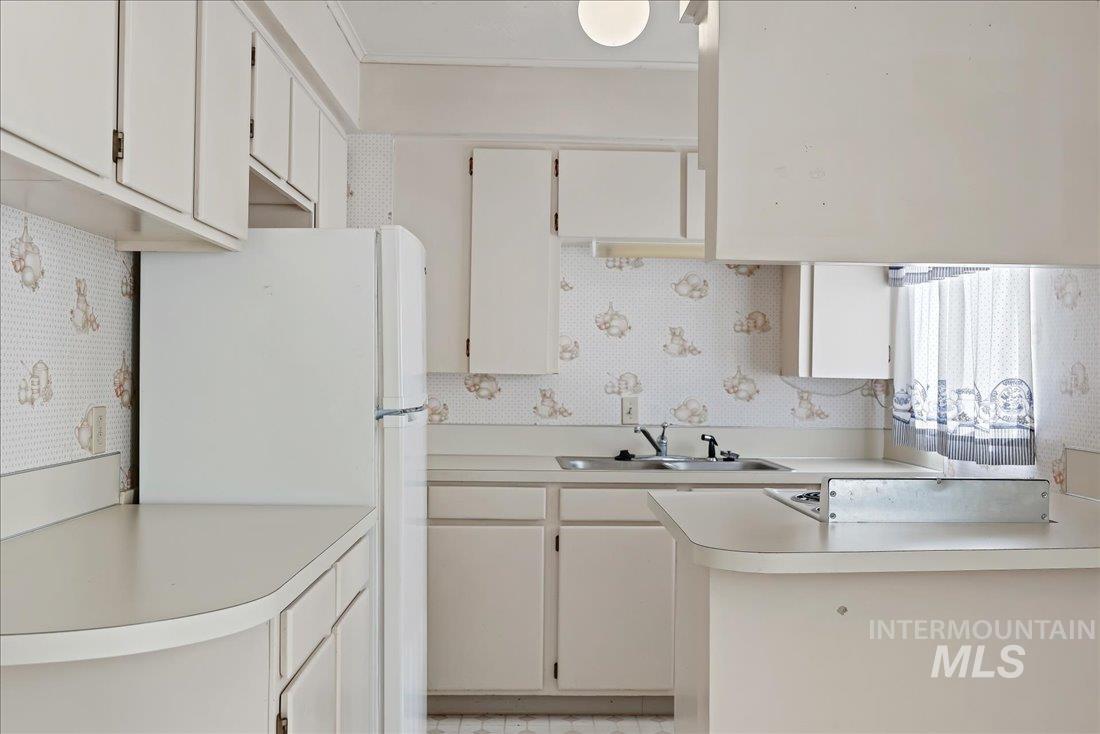 Kitchen featuring freestanding refrigerator, light countertops, and white cabinets