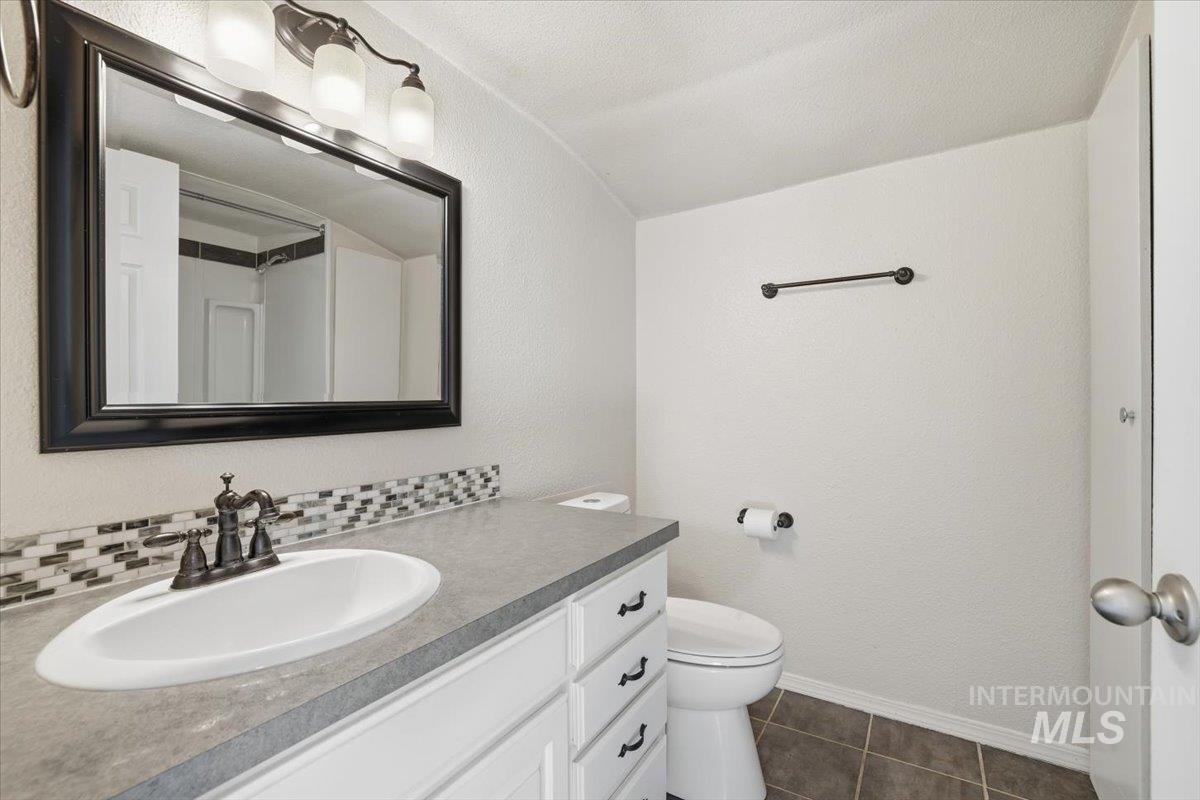 Bathroom featuring vanity, dark tile patterned flooring, and a textured wall