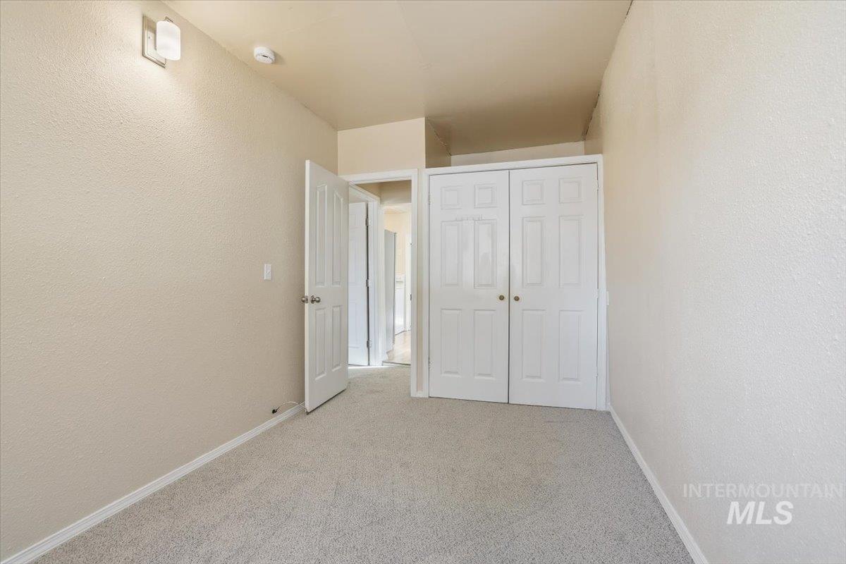 Unfurnished bedroom with a textured wall, light carpet, and a closet