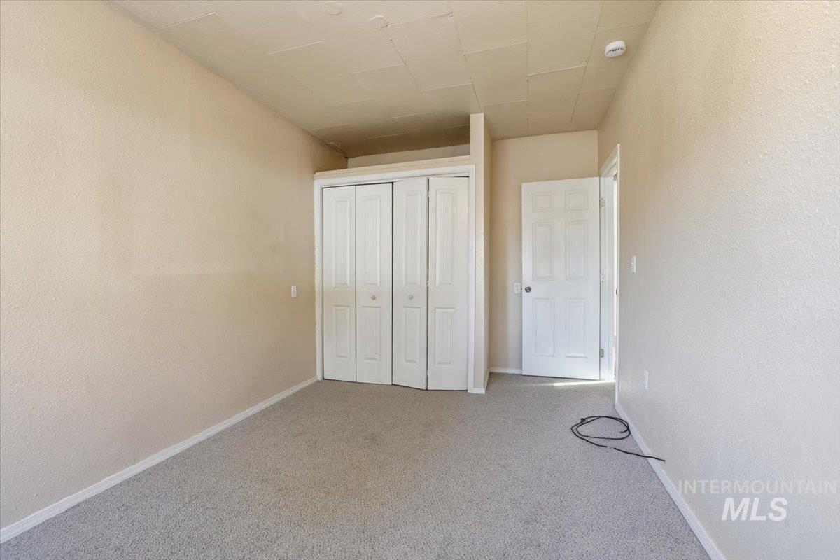 Unfurnished bedroom featuring a textured wall, carpet floors, and a closet