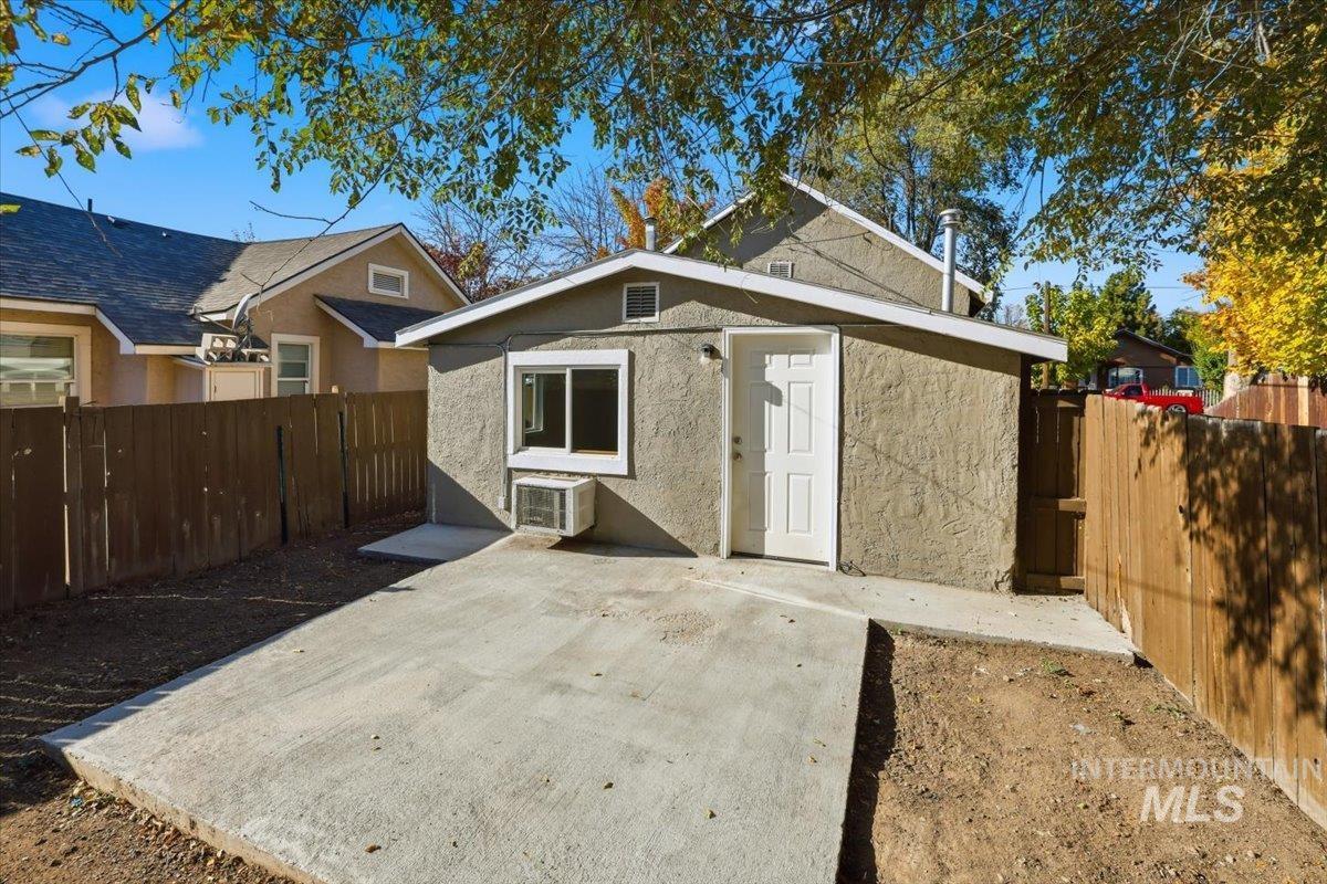 Back of house featuring a patio, a fenced backyard, stucco siding, and a wall unit AC