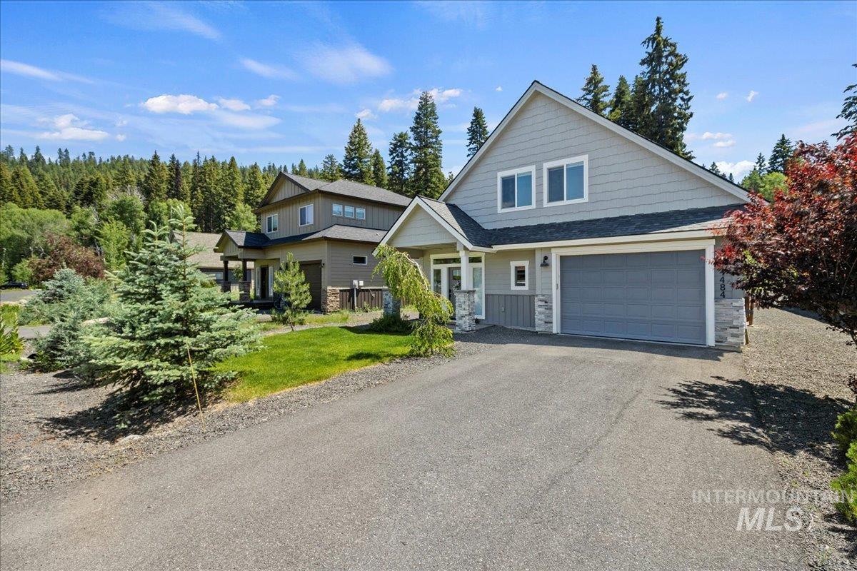 View of front of home with stone siding, driveway, and a garage
