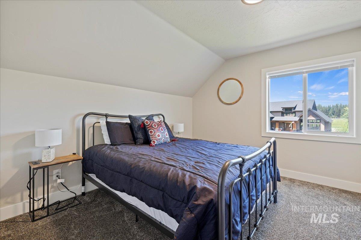 Carpeted bedroom featuring baseboards and lofted ceiling