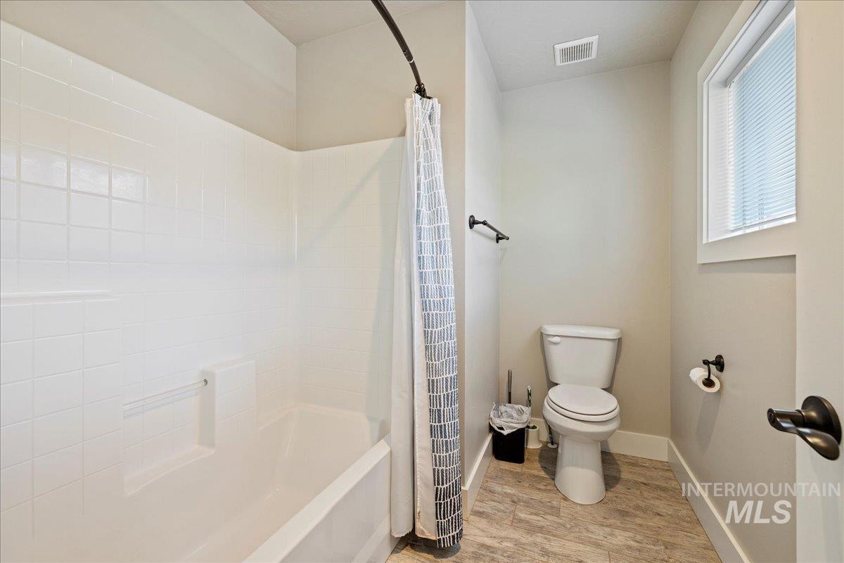 Bathroom featuring wood finished floors and shower / bath combo with shower curtain