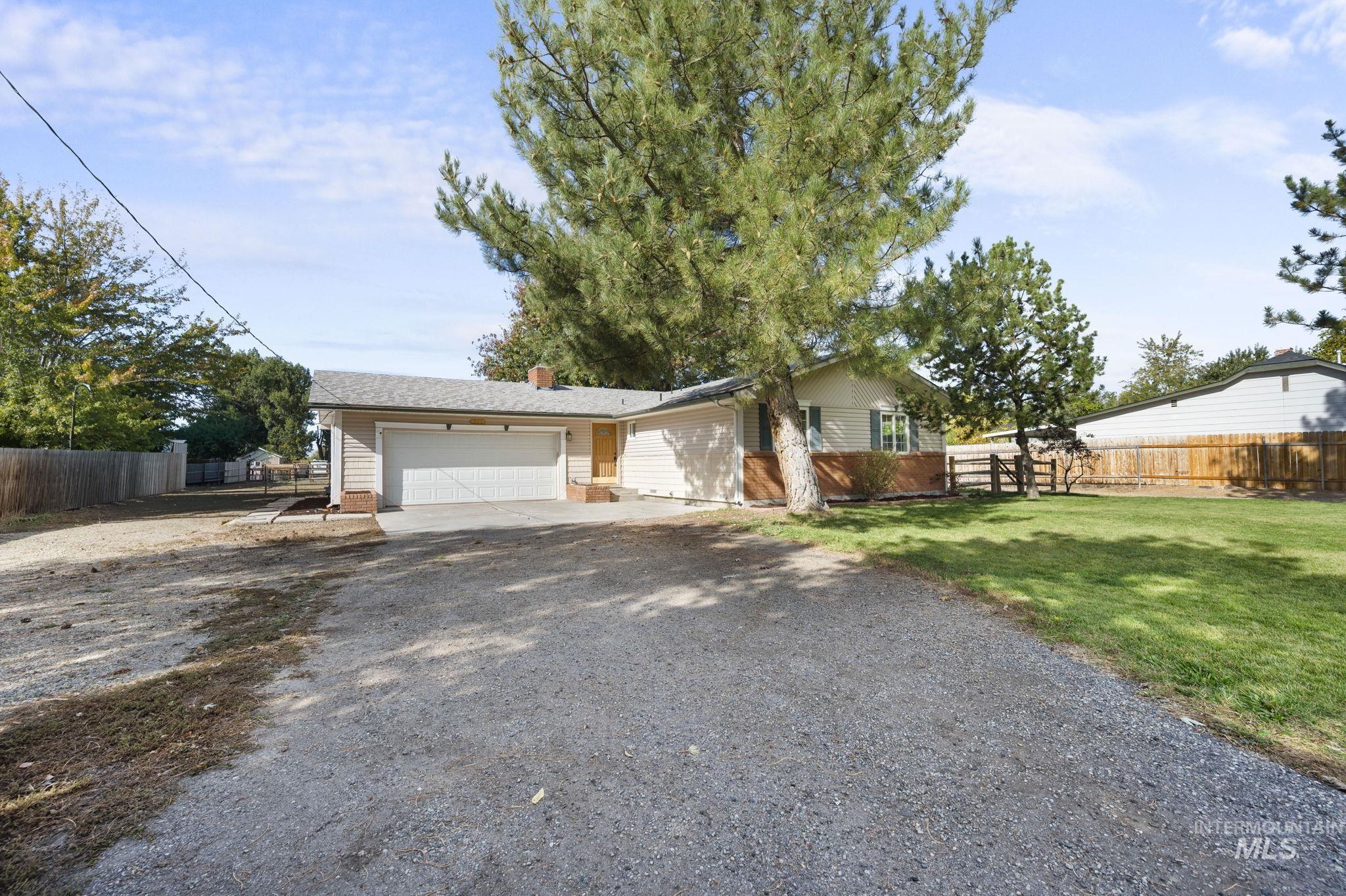 View of front of property featuring gravel driveway, an attached garage, and a chimney