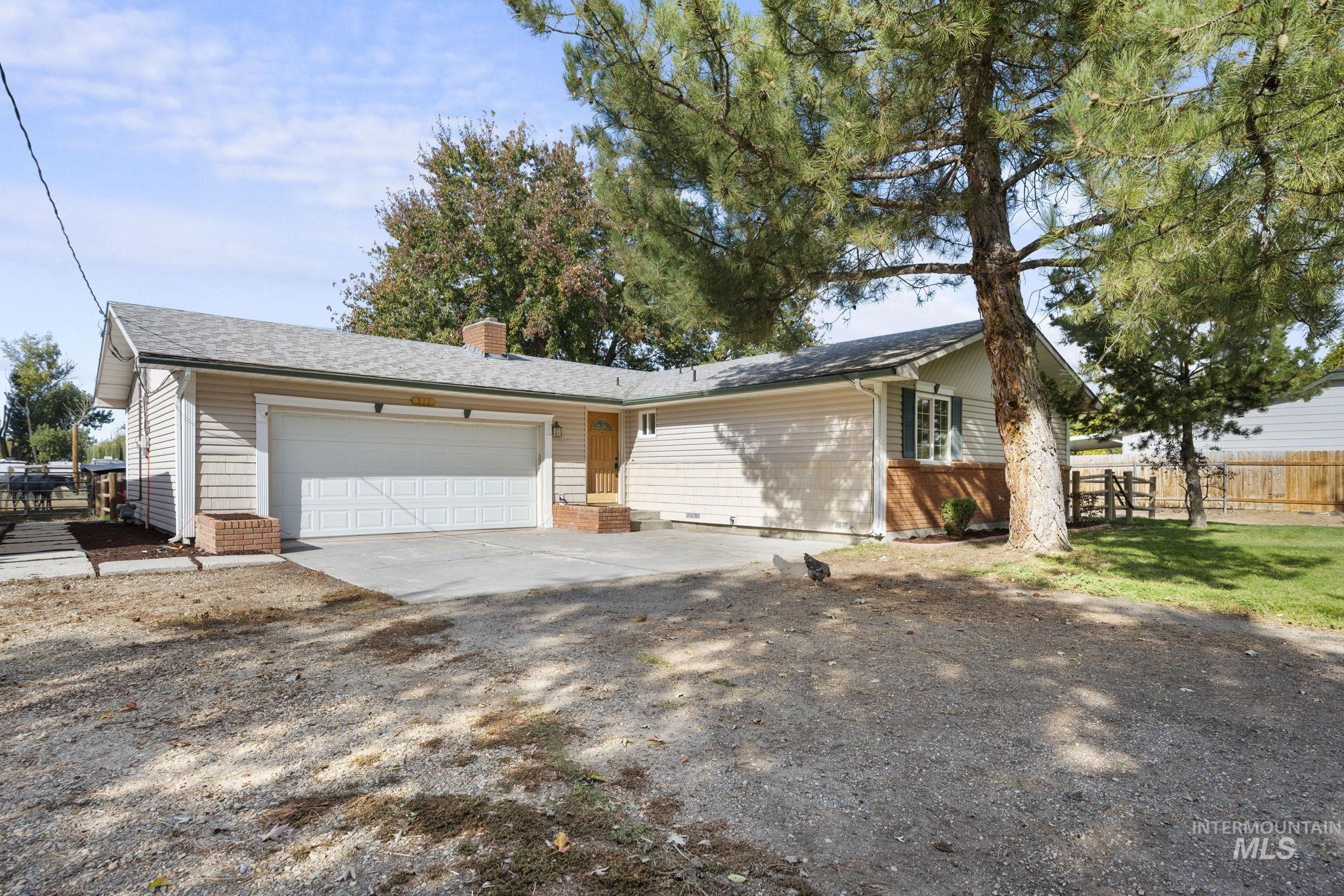 View of front of home featuring a chimney, driveway, and a garage