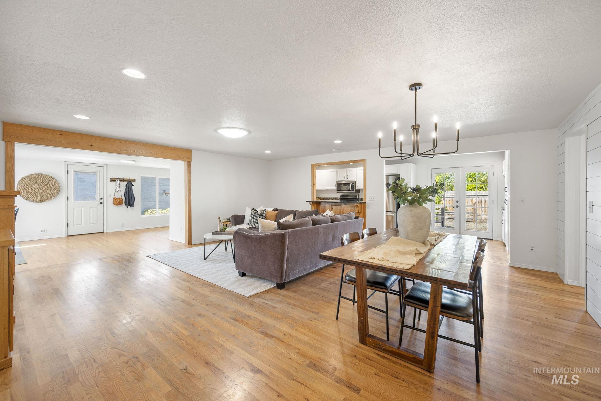 Dining area with a chandelier, light wood finished floors, a textured ceiling, and recessed lighting