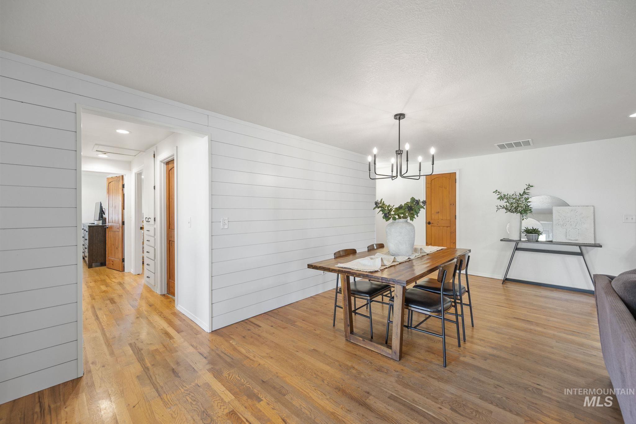 Dining area with light wood-style flooring, a chandelier, recessed lighting, and wood walls