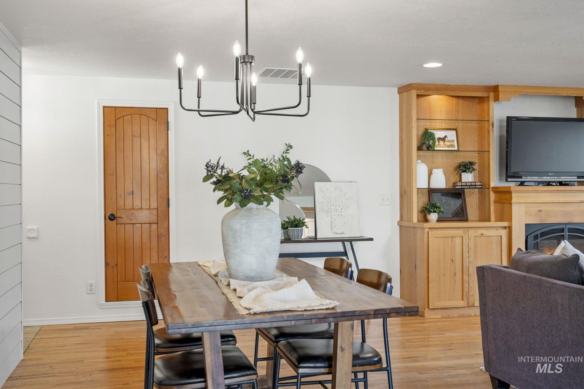 Dining area featuring a warm lit fireplace, light wood finished floors, a chandelier, and recessed lighting