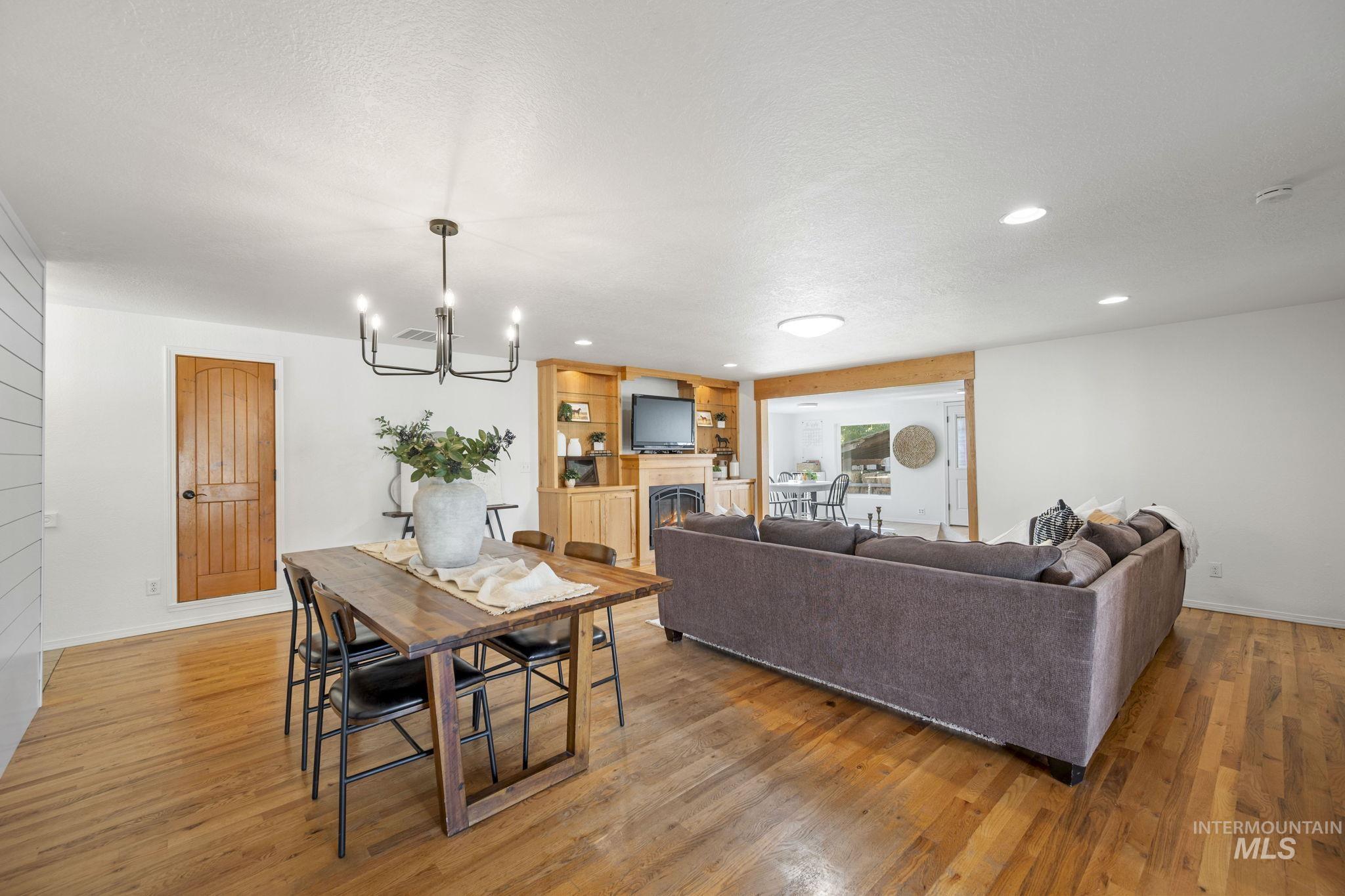 Dining space with a lit fireplace, recessed lighting, light wood finished floors, a chandelier, and a textured ceiling