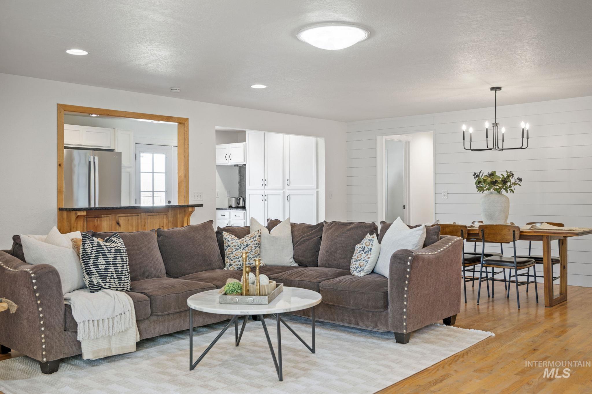 Living room with light wood-style floors, a textured ceiling, a chandelier, and recessed lighting