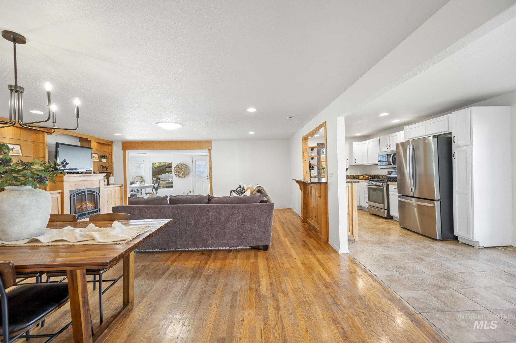 Living area with a lit fireplace, recessed lighting, light wood-style floors, and a chandelier