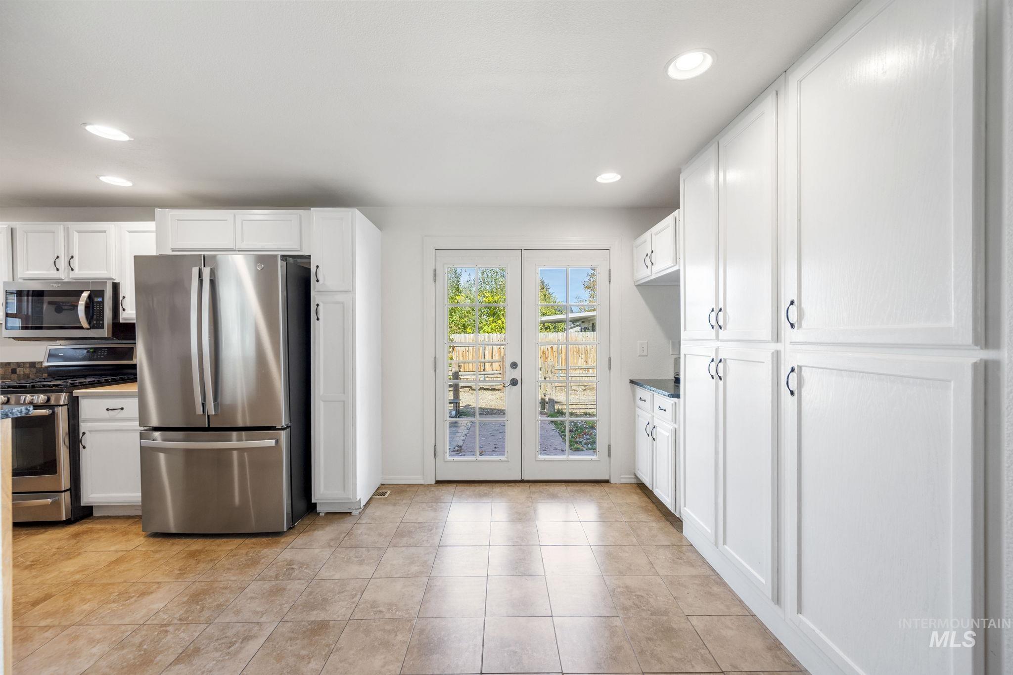 Kitchen featuring white cabinetry, stainless steel appliances, french doors, recessed lighting, and dark countertops