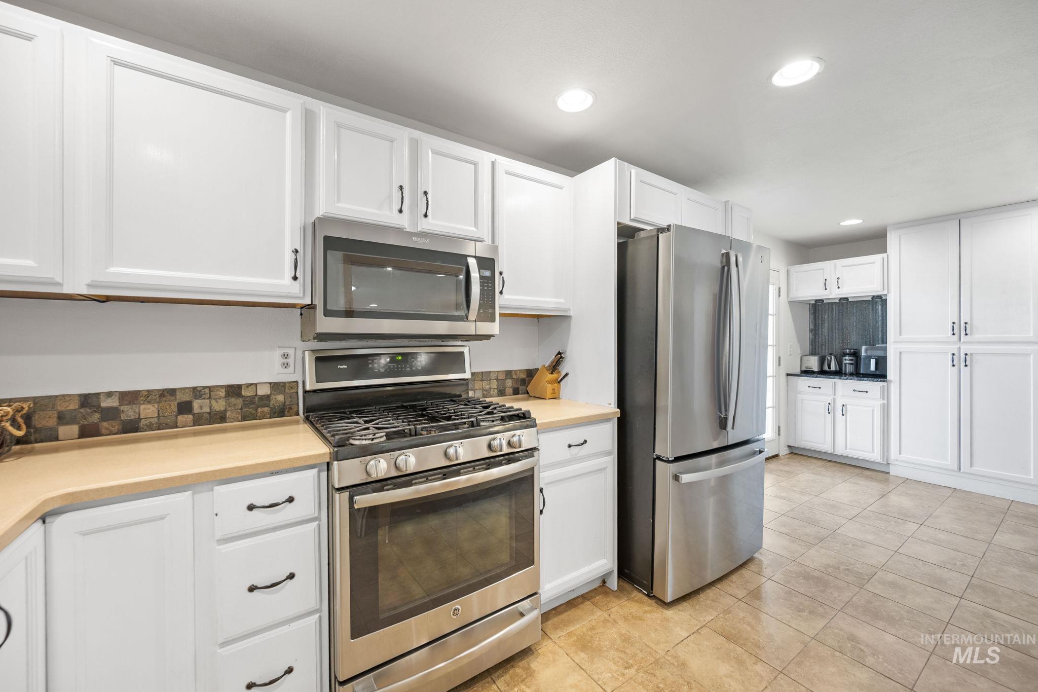 Kitchen with appliances with stainless steel finishes, white cabinetry, recessed lighting, light tile patterned floors, and light countertops