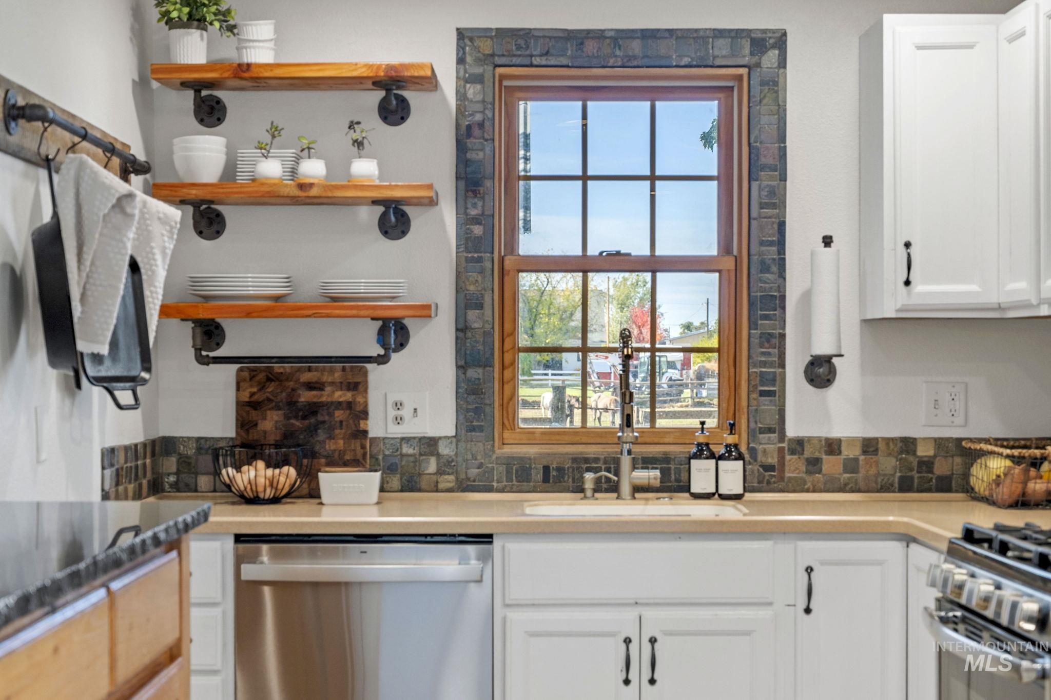 Kitchen featuring stainless steel appliances, white cabinetry, open shelves, and backsplash
