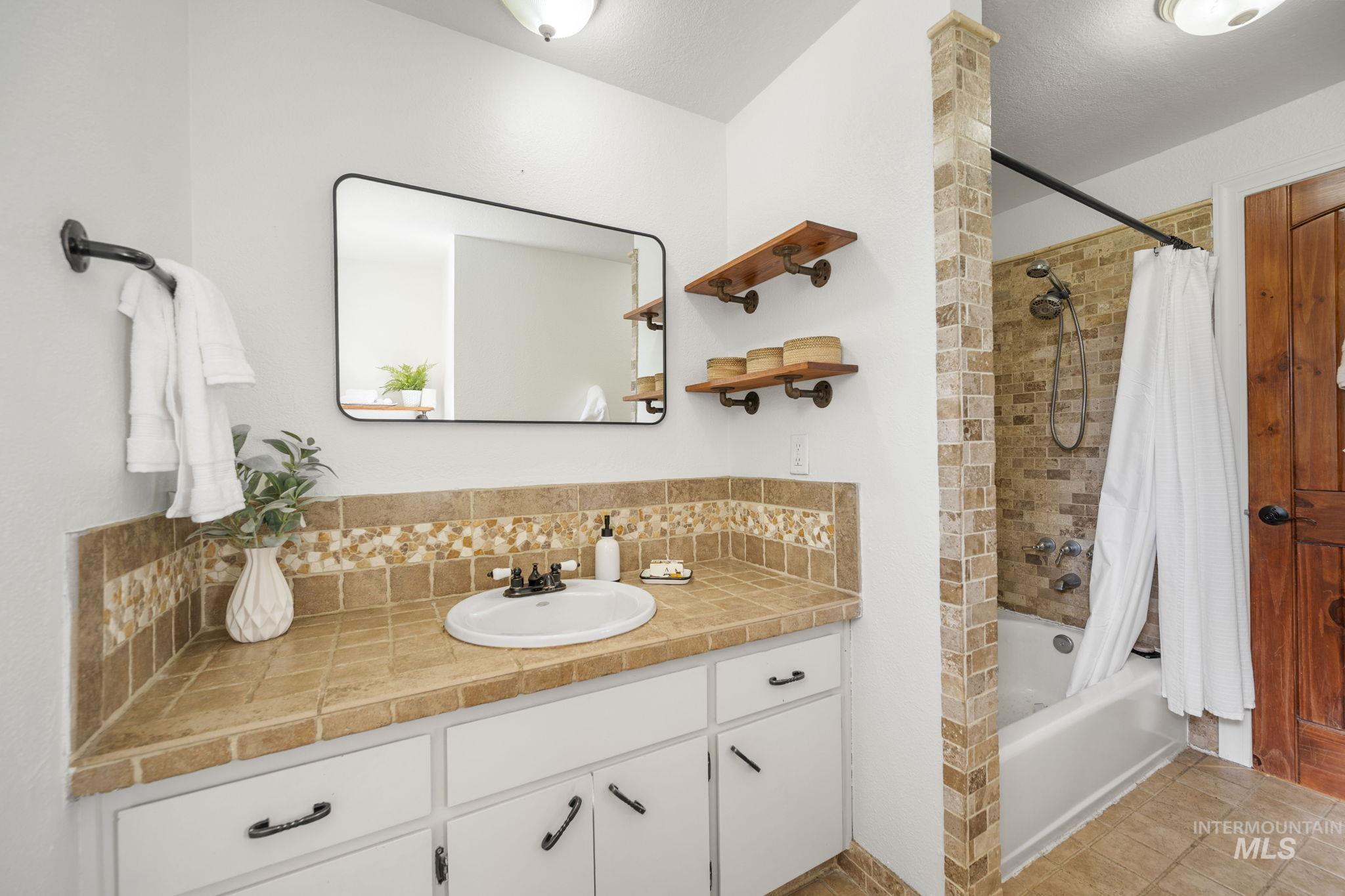 Full bath with shower / bath combination with curtain, vanity, backsplash, light tile patterned flooring, and a textured ceiling
