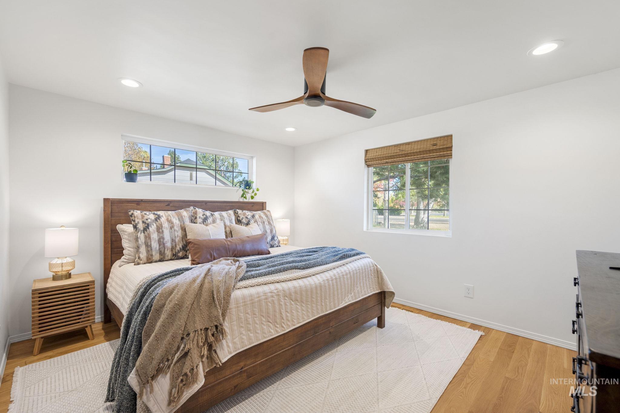 Bedroom with multiple windows, light wood finished floors, recessed lighting, and a ceiling fan