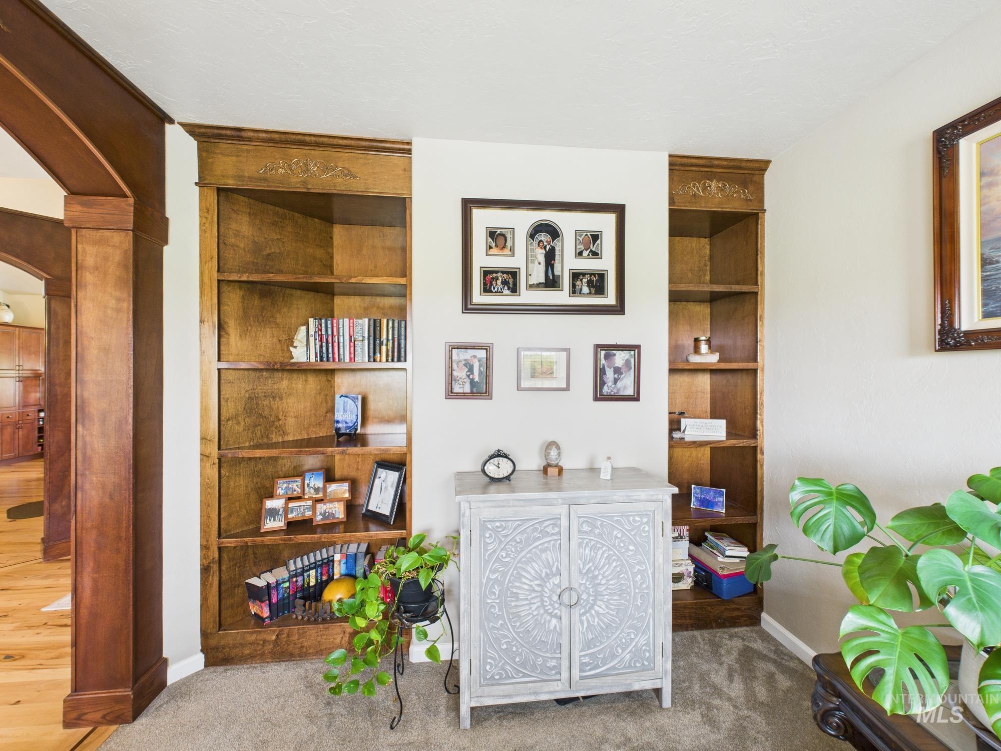 Carpeted office space featuring arched walkways and built in shelves
