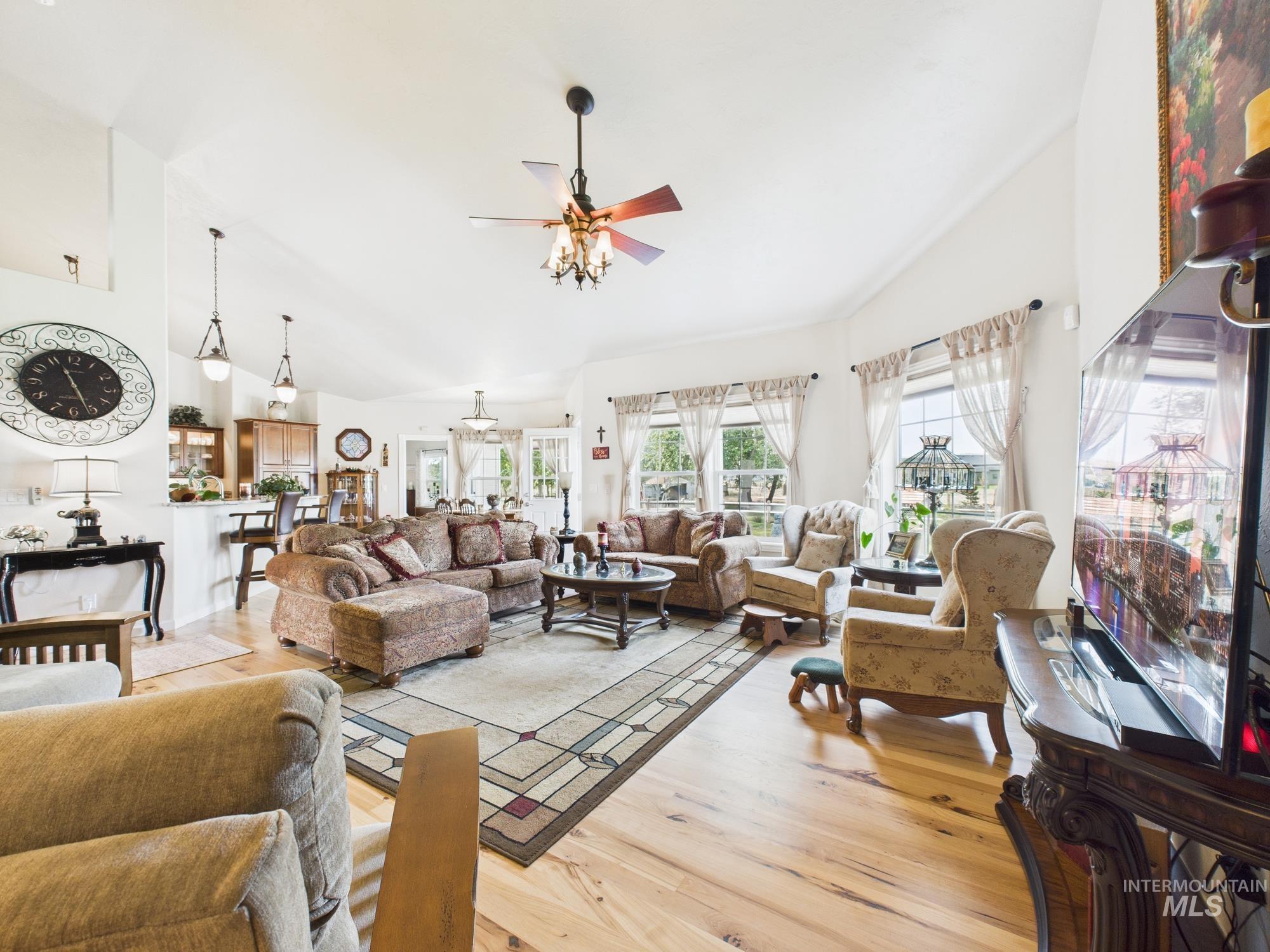 Living area featuring high vaulted ceiling, wood finished floors, and ceiling fan