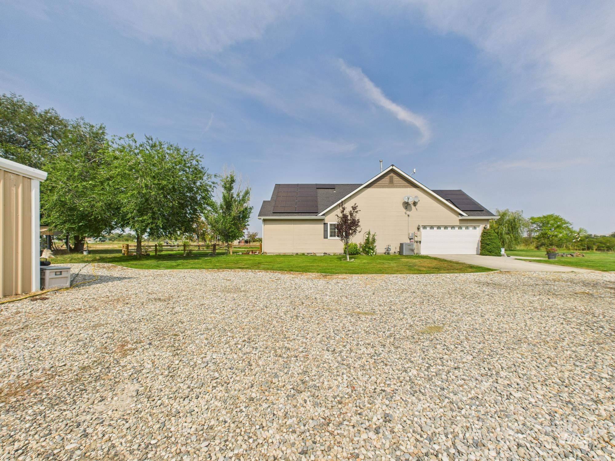View of side of property featuring roof mounted solar panels, concrete driveway, and a garage