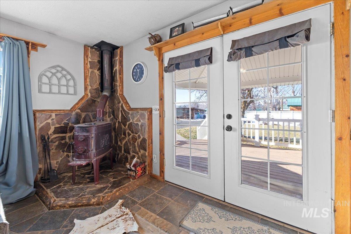 Doorway to outside featuring french doors, stone tile floors, and a wood stove