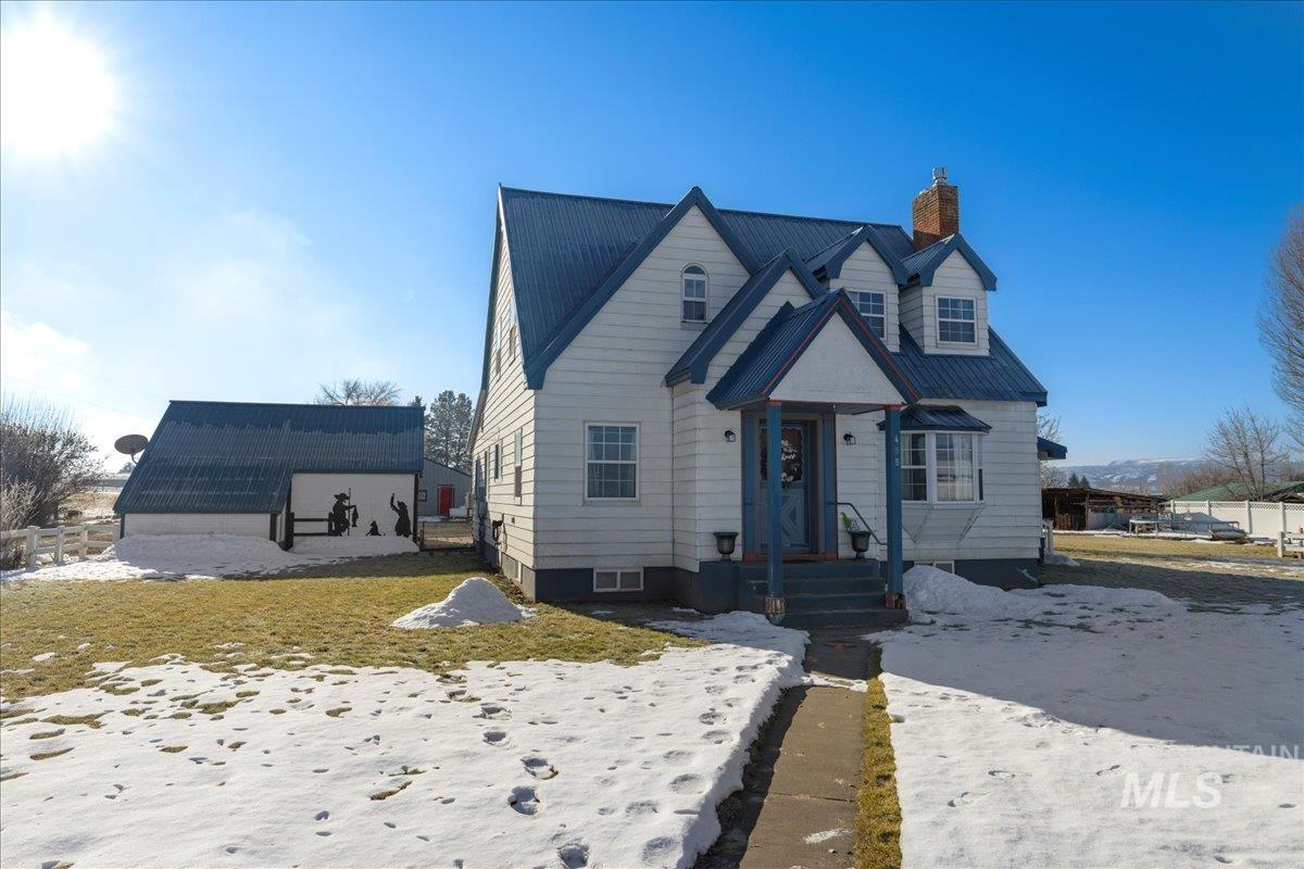 View of front of property featuring a chimney, a metal roof, and an outdoor structure