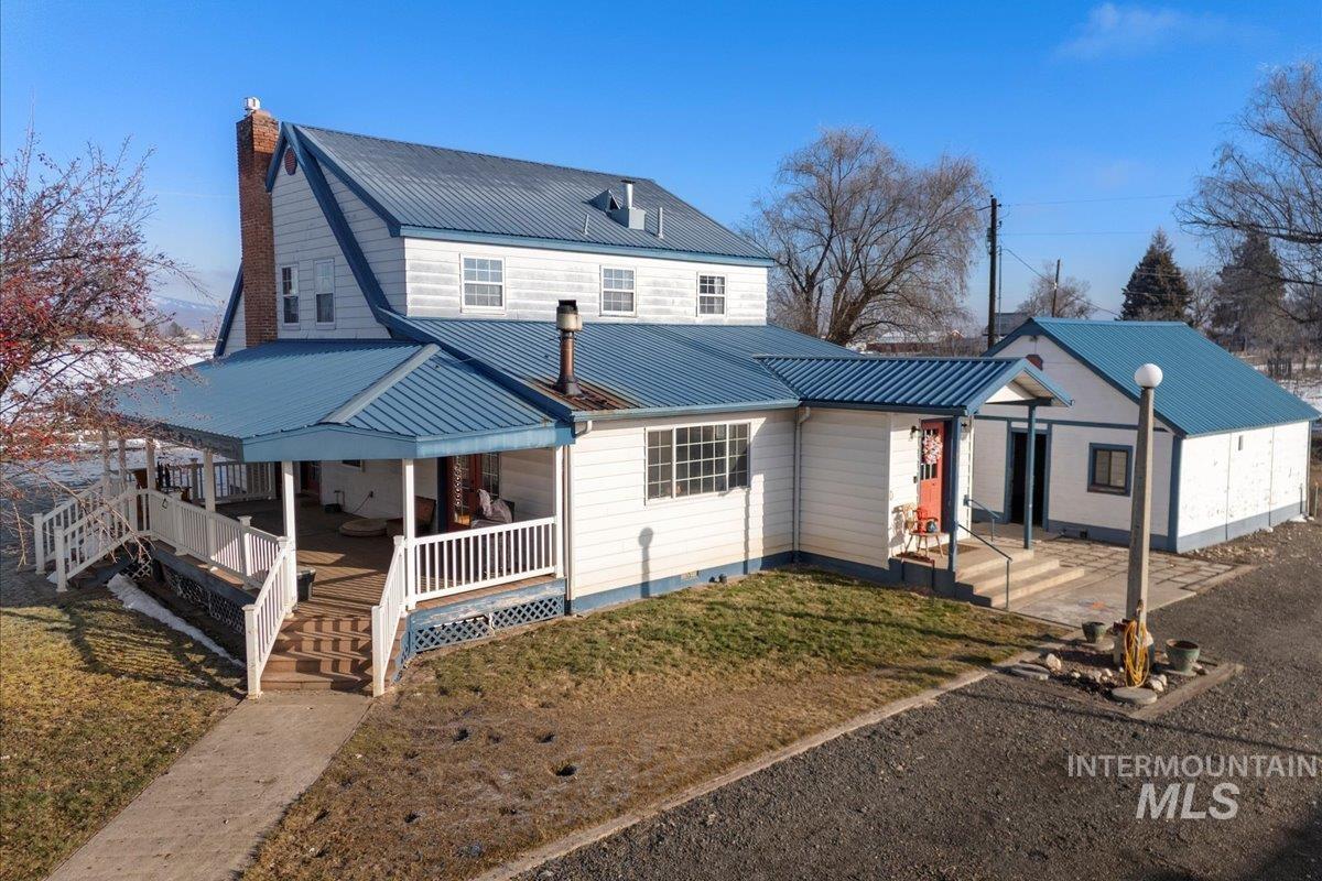 View of front of property featuring a porch, a chimney, a metal roof, and a front lawn
