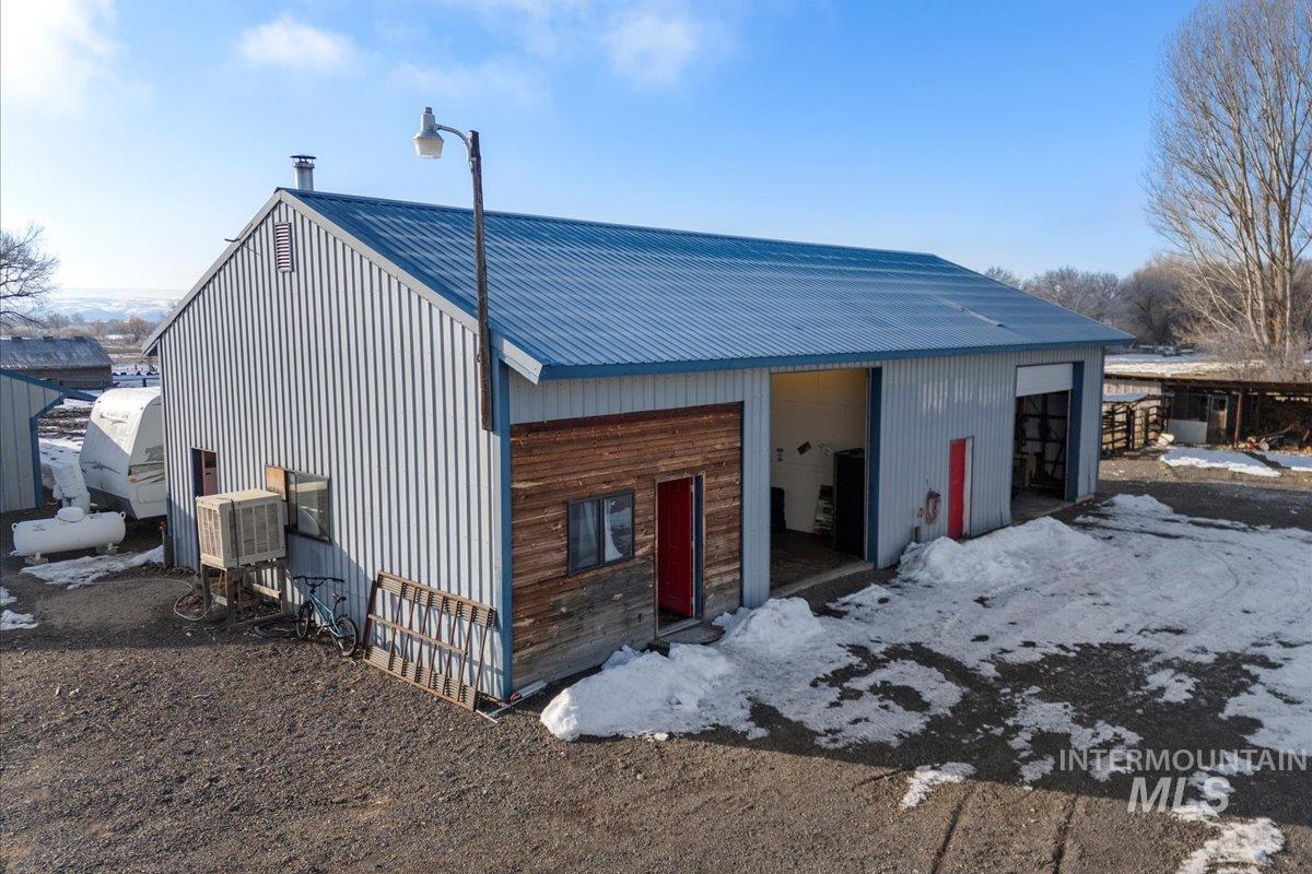 View of front of house featuring a metal roof, an outdoor structure, an outbuilding, and cooling unit
